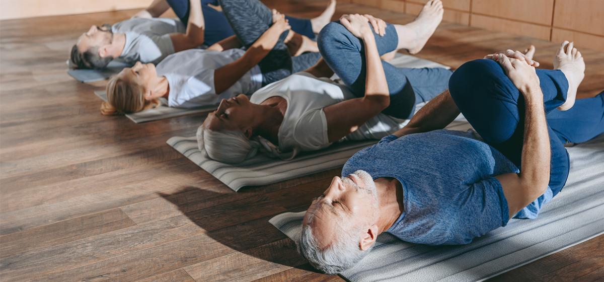 Group of people doing Feldenkrais stretching exercise in studio