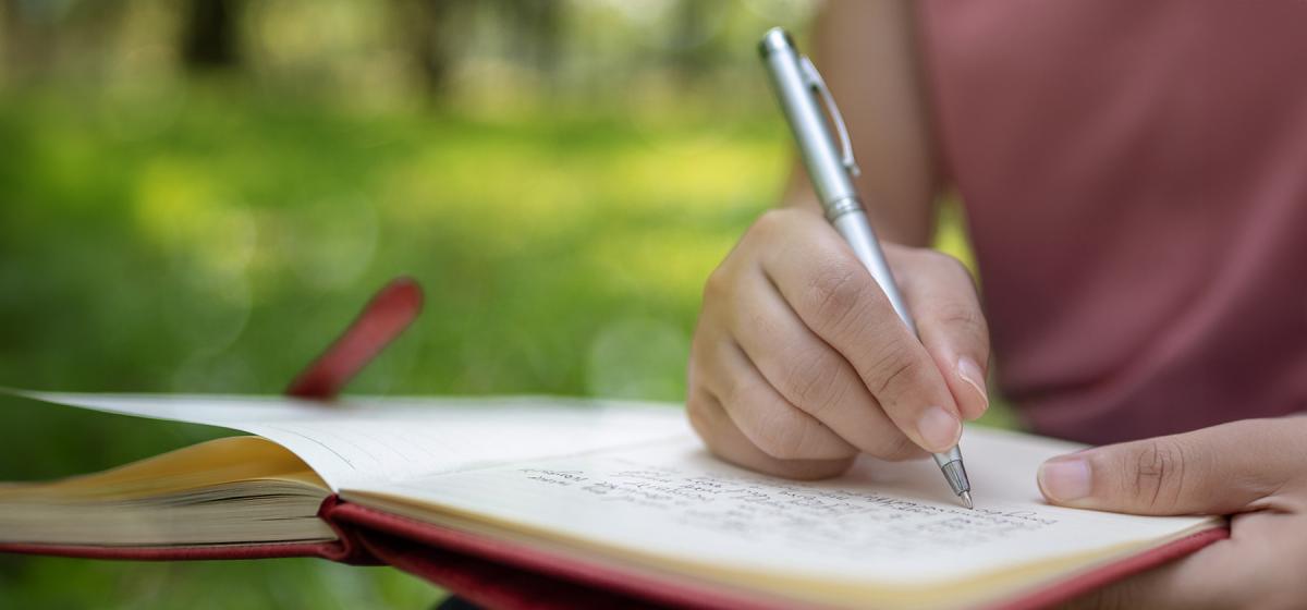 Woman writing in a notebook outside