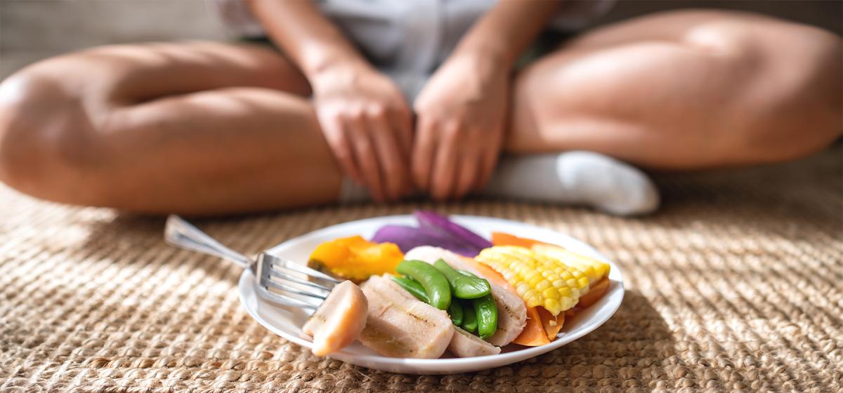 Person meditating with a plate of healthy food.