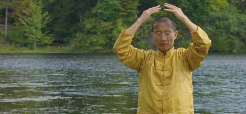 Mingtong Gu practicing qigong in front of a lake