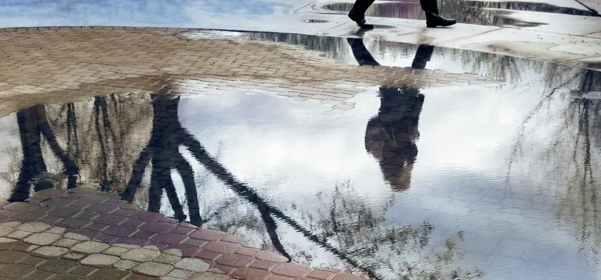 Someone's reflection in a puddle on the street