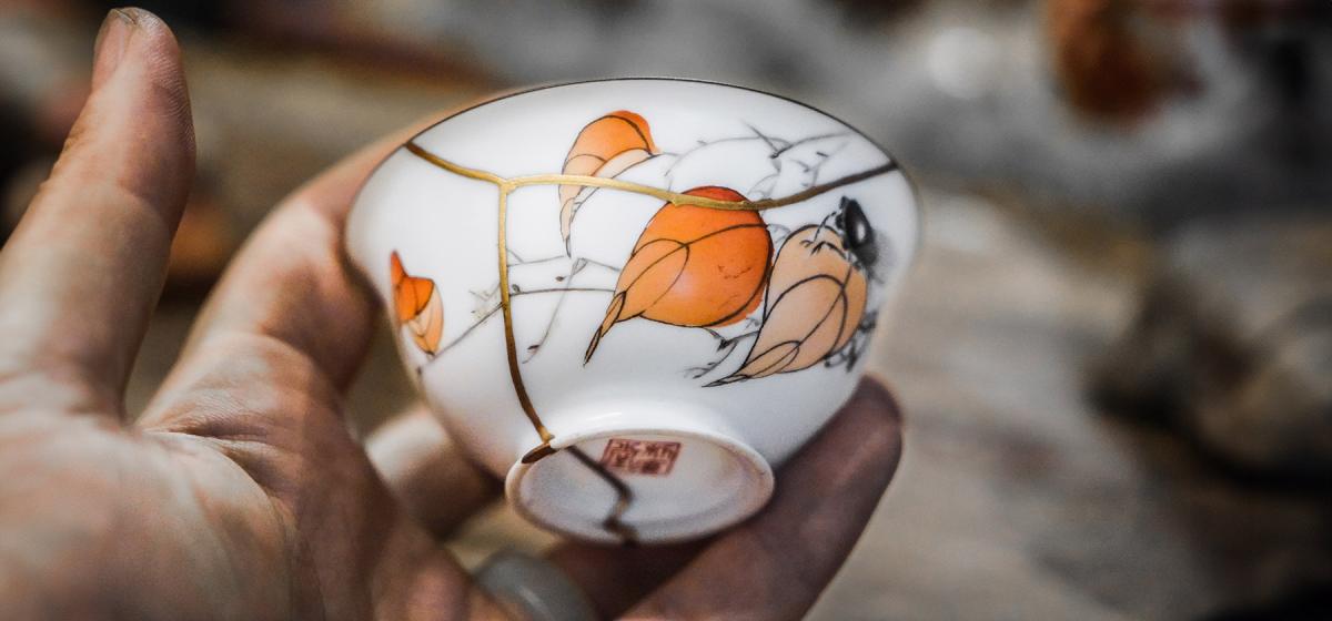 Hand holding a bowl mended with the Kintsugi method, with exposed gold