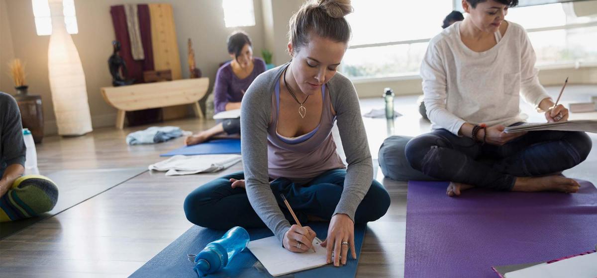 People writing in journals in yoga class