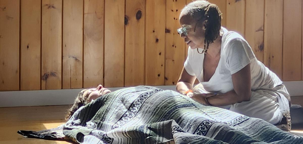 End-of-life doula kneeling next to a grieving person and helping them heal