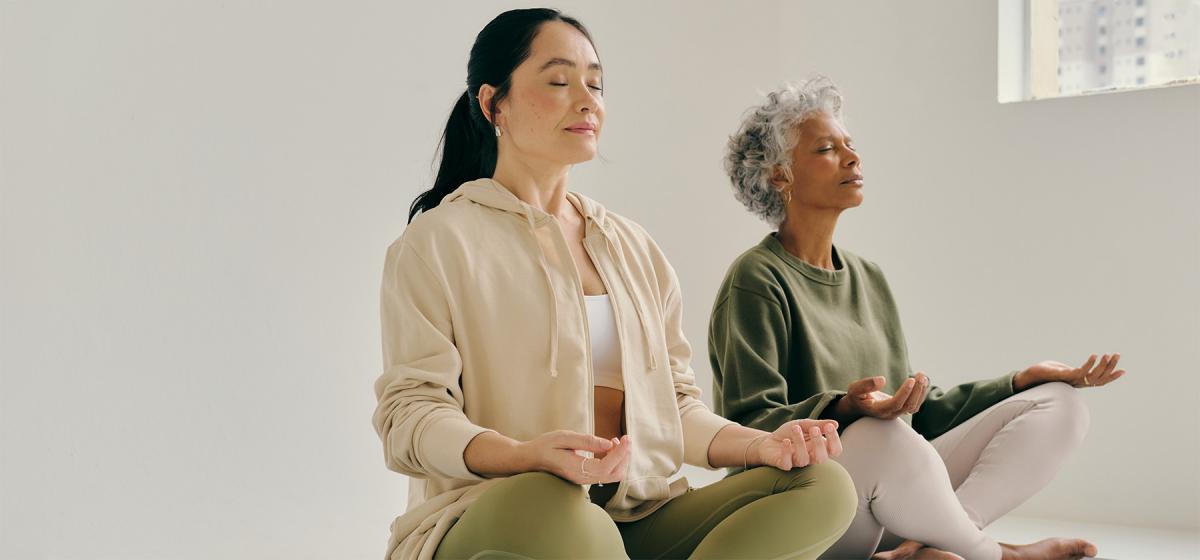 Two people meditating in a bright white room