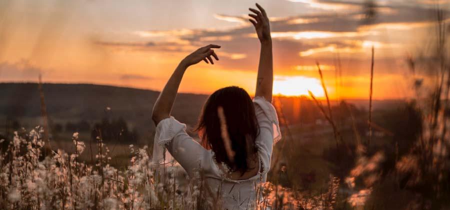 Woman dancing in a field at sunset