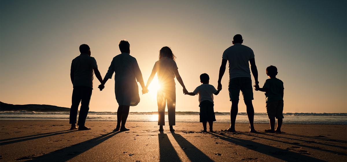 Multigenerational family standing in front of sunset