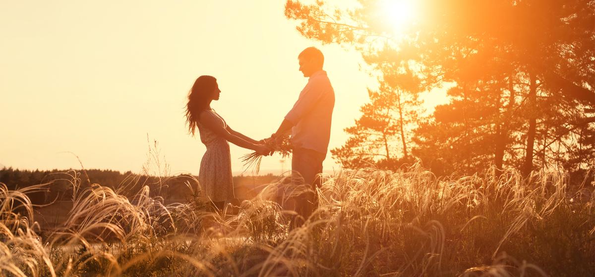 Couple holding hands in front of dramatic sunset