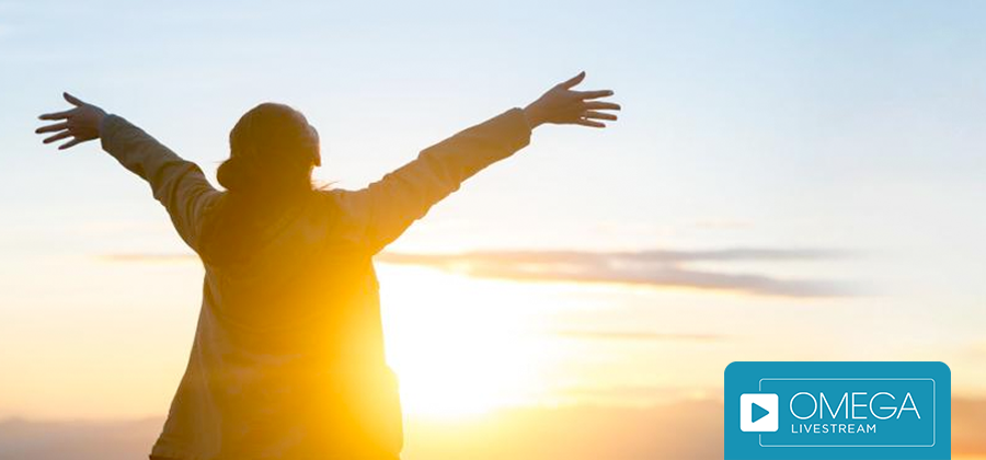 Woman looking at the sunset with open arms