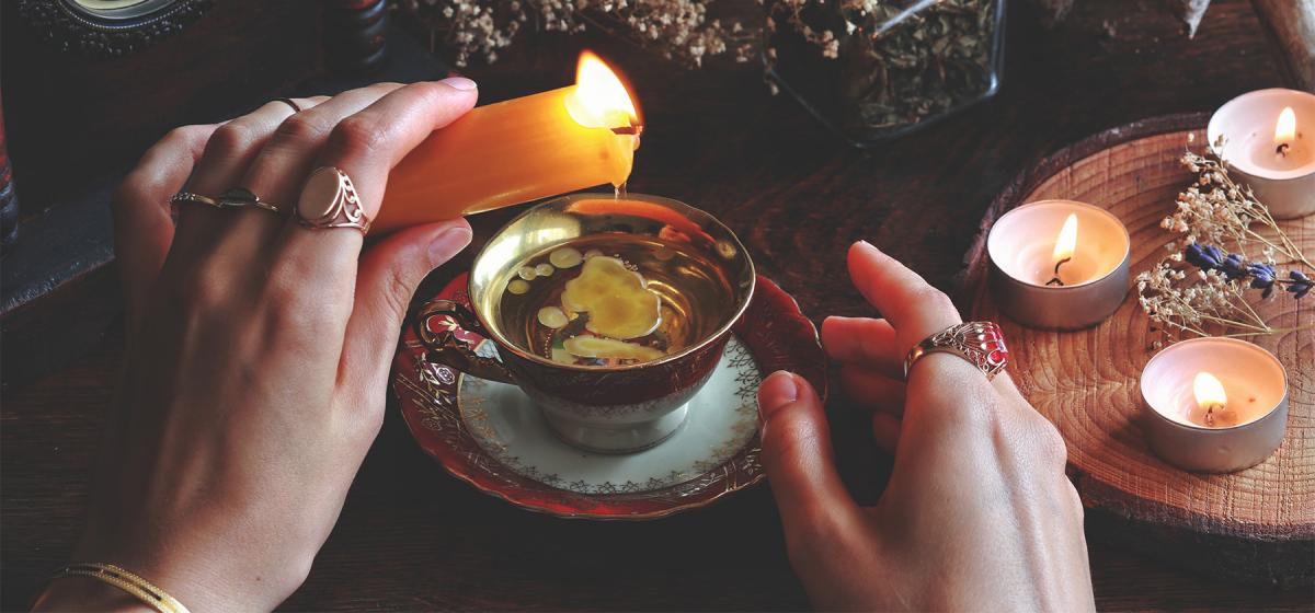 Person lighting a candle on a table full of spiritual objects