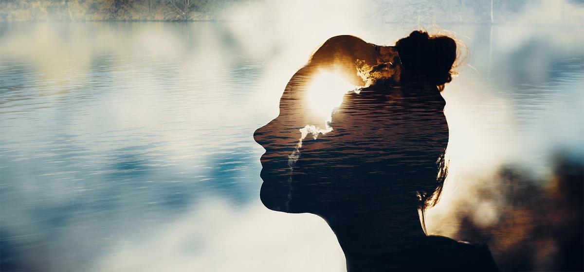 Double exposure image of woman's head with bright sun in sky