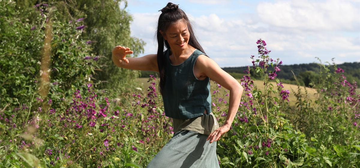 Mimi Kuo-Deemer practicing qigong in a field of flowers