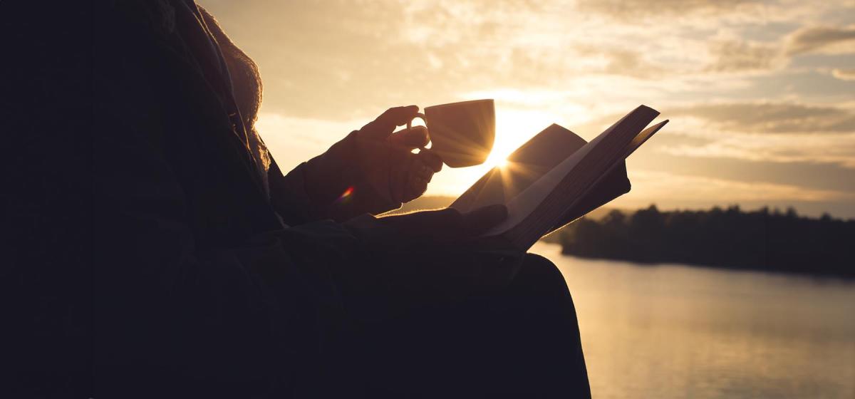 Woman drinking tea and reading a book outside