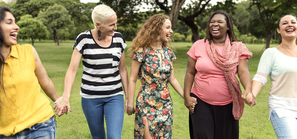 Group of middle aged women holding hands joyfully on a retreat