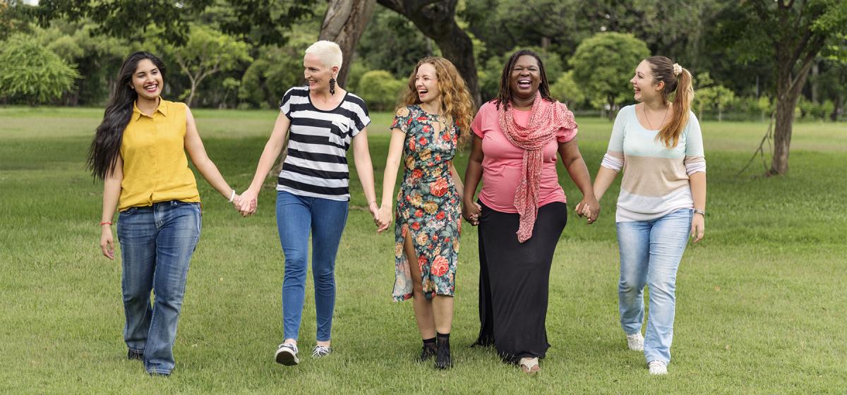Group of women walking through a field holding hands