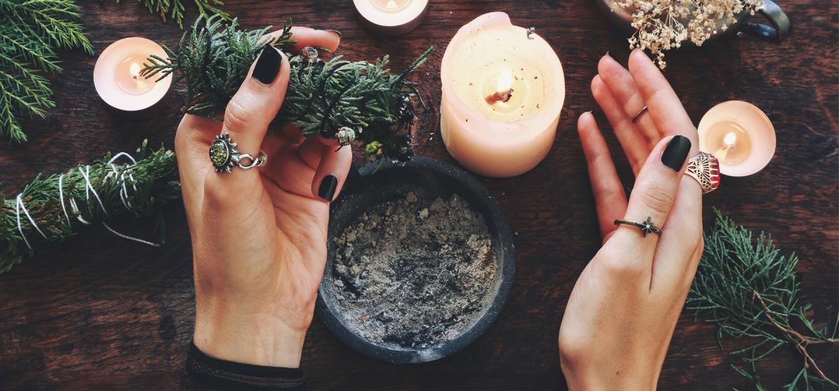 Person's hands with cedar and candles performing ritual