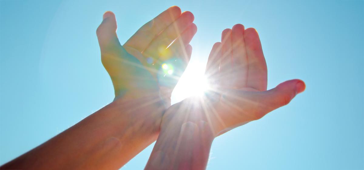 Hands channeling light from the sky