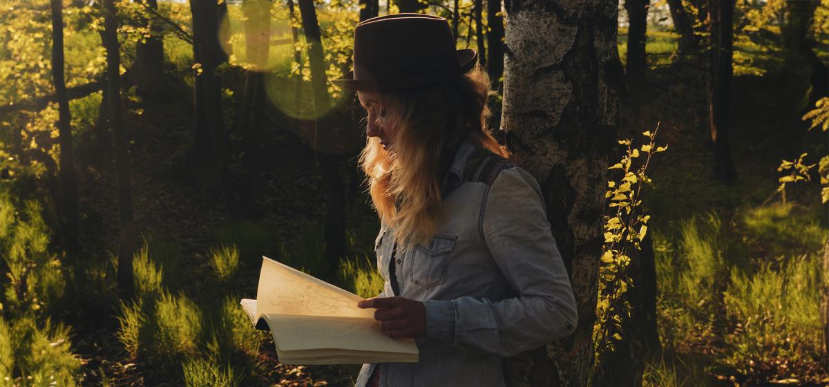 Woman writing in a journal in the woods