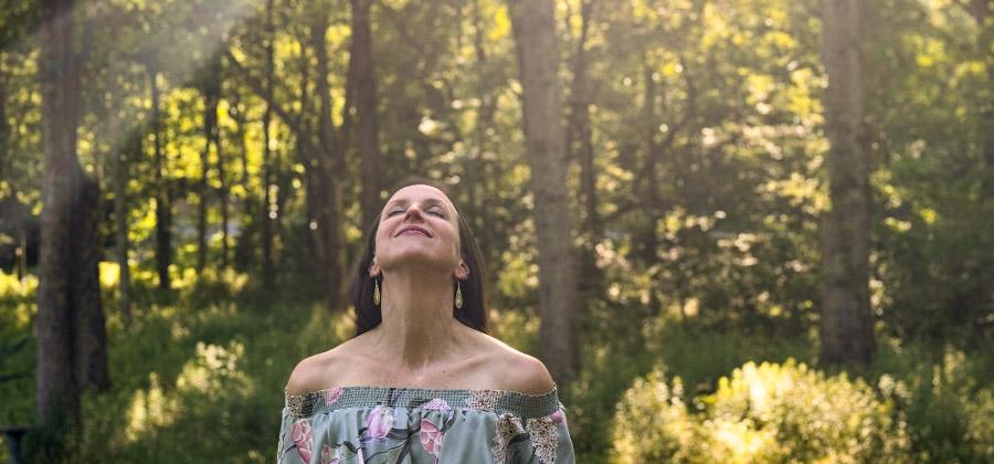 Cheryl Engelhardt doing a grounding somatic practice outside in a forest