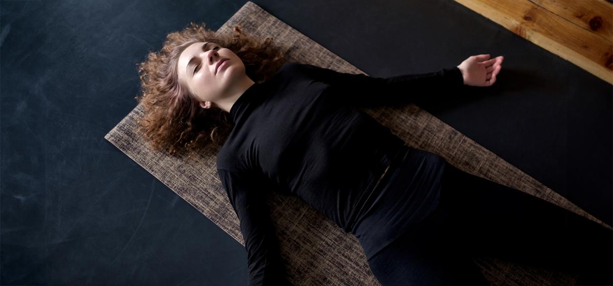 Woman laying on the floor in corpse pose in a yoga nidra class