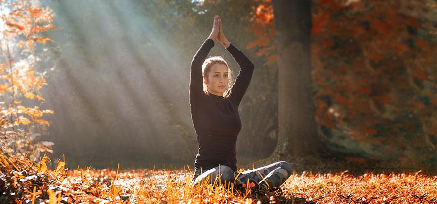 Woman in yoga pose outdoors in the fall.