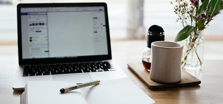 Laptop, mug, and notebook on a desk