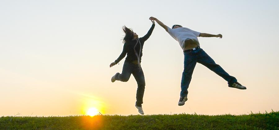 Two people dancing joyfully at sunset