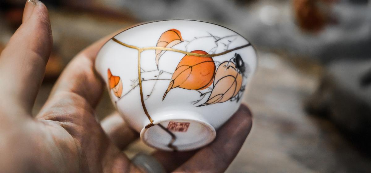 Hand holding a patched kintsugi cup