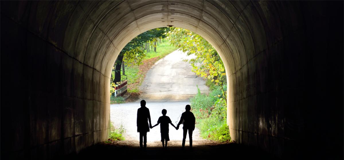 Family standing at the opening of a tunnel holding hands