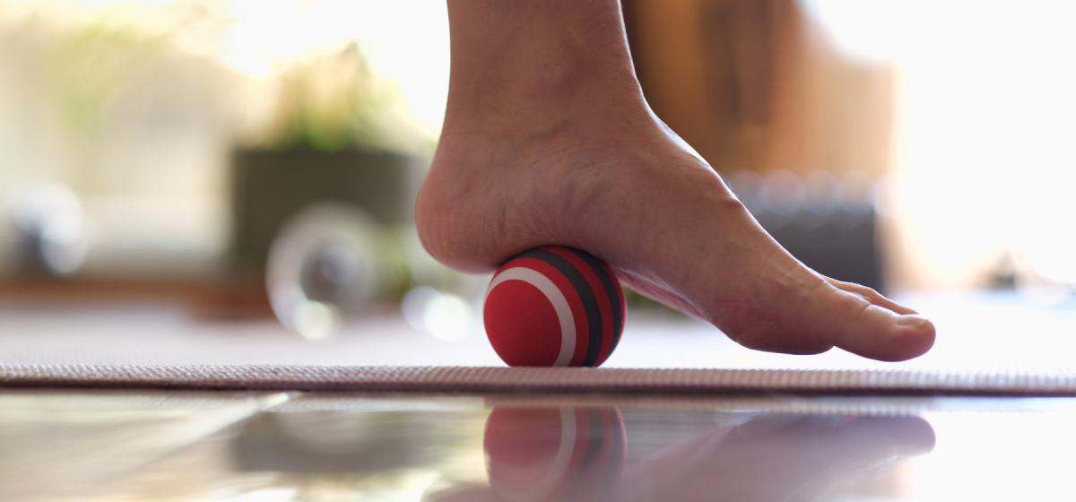 Person conducting myofascial stretch on their foot with tennis ball