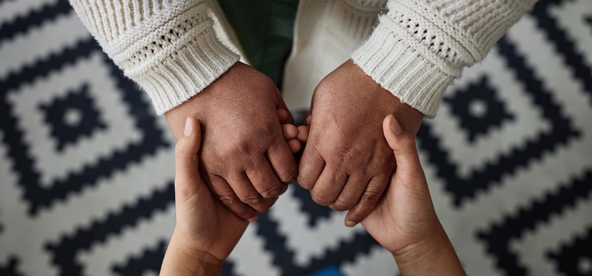 Someone tenderly holding another person's hands to comfort them