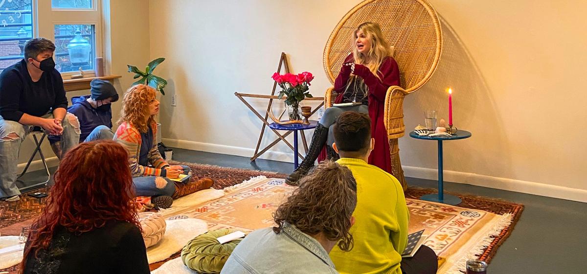 Danielle Dulsky leading a class, in a room with candles and magical items