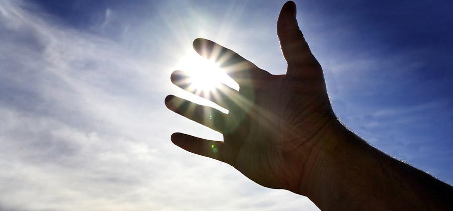 Hand reaching towards the sun