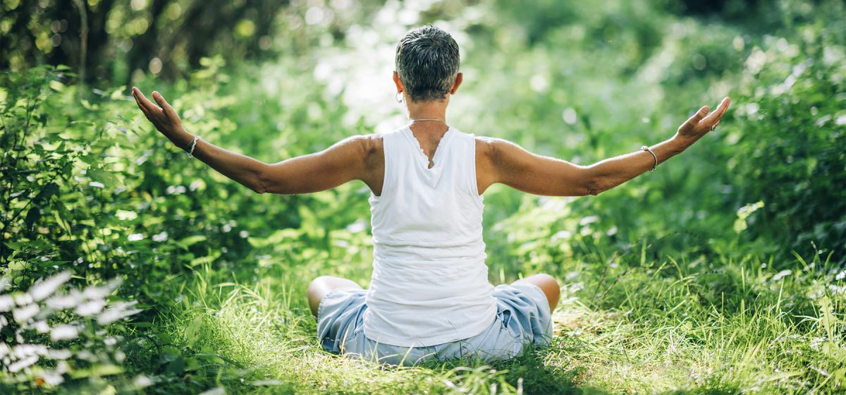 Woman meditating in a sunlit forest