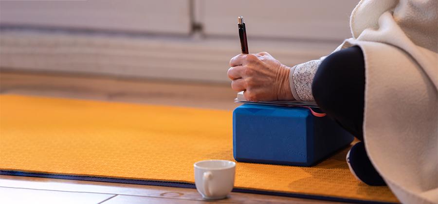 A person writing in their journal in a yoga class.