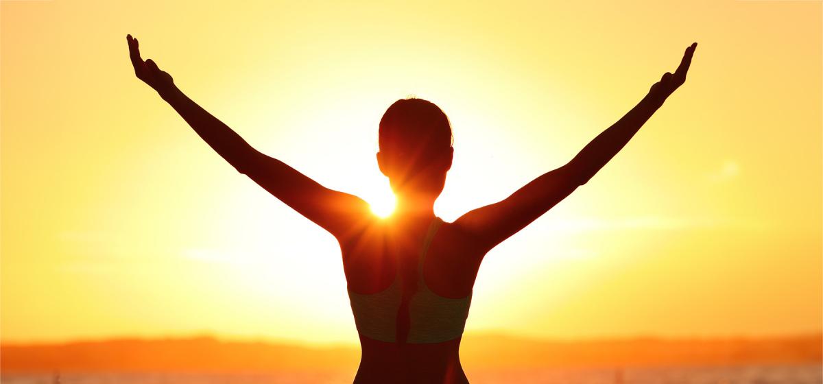 Woman with her arms up at sunset
