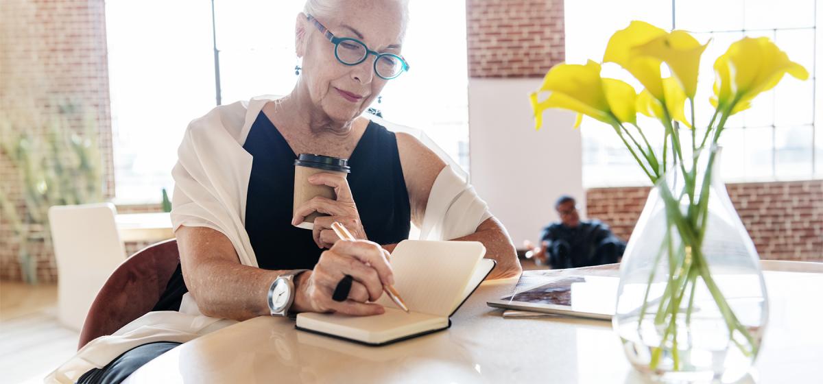 Woman writing in her journal in a coffee shop.
