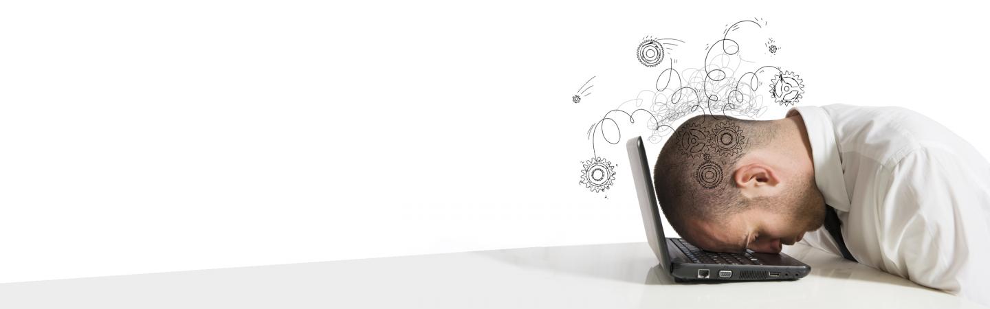 Stressed office worker with head on laptop, symbolizing mental overload and the negative effects of multitasking.