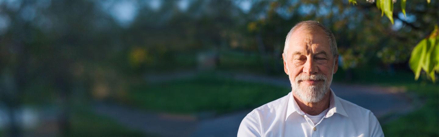 Peaceful older man smiling with eyes closed practicing mindfulness, self-compassion, and lovingkindness meditation as part of daily wellness and emotional resilience.