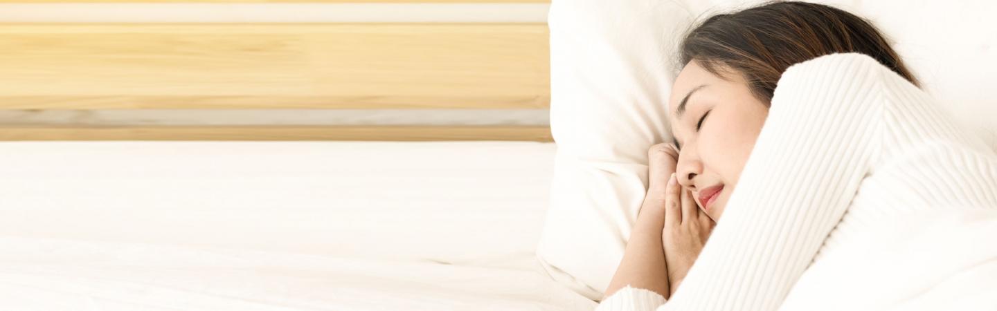 Peaceful woman sleeping in bed, illustrating steps to remember dreams and explore lucid dreaming.