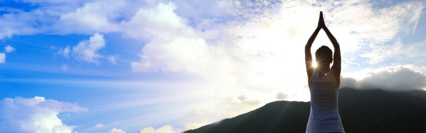 Woman practicing sadhana outdoors at sunrise, demonstrating daily spiritual practice and mindfulness.