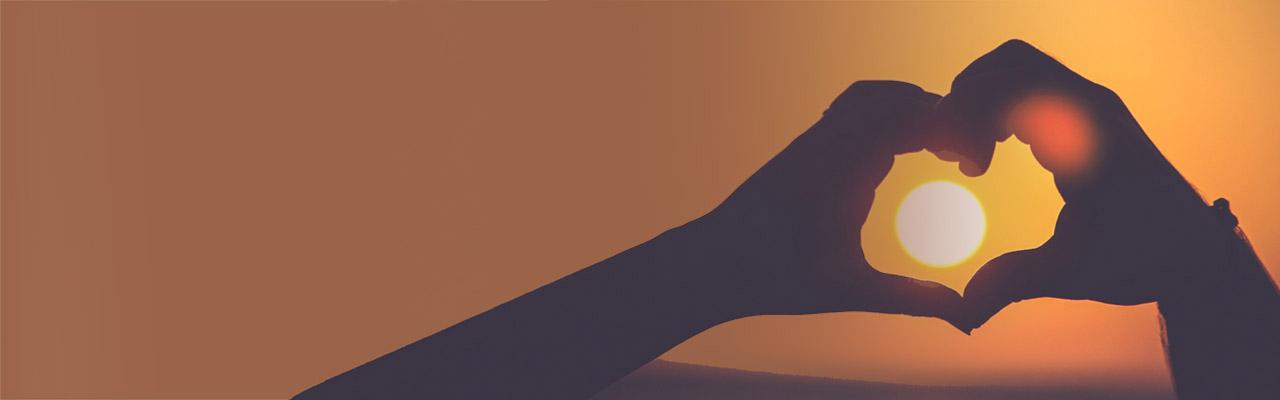 Hands in heart shape around the sun, symbolizing love and life lessons from near-death experiences.