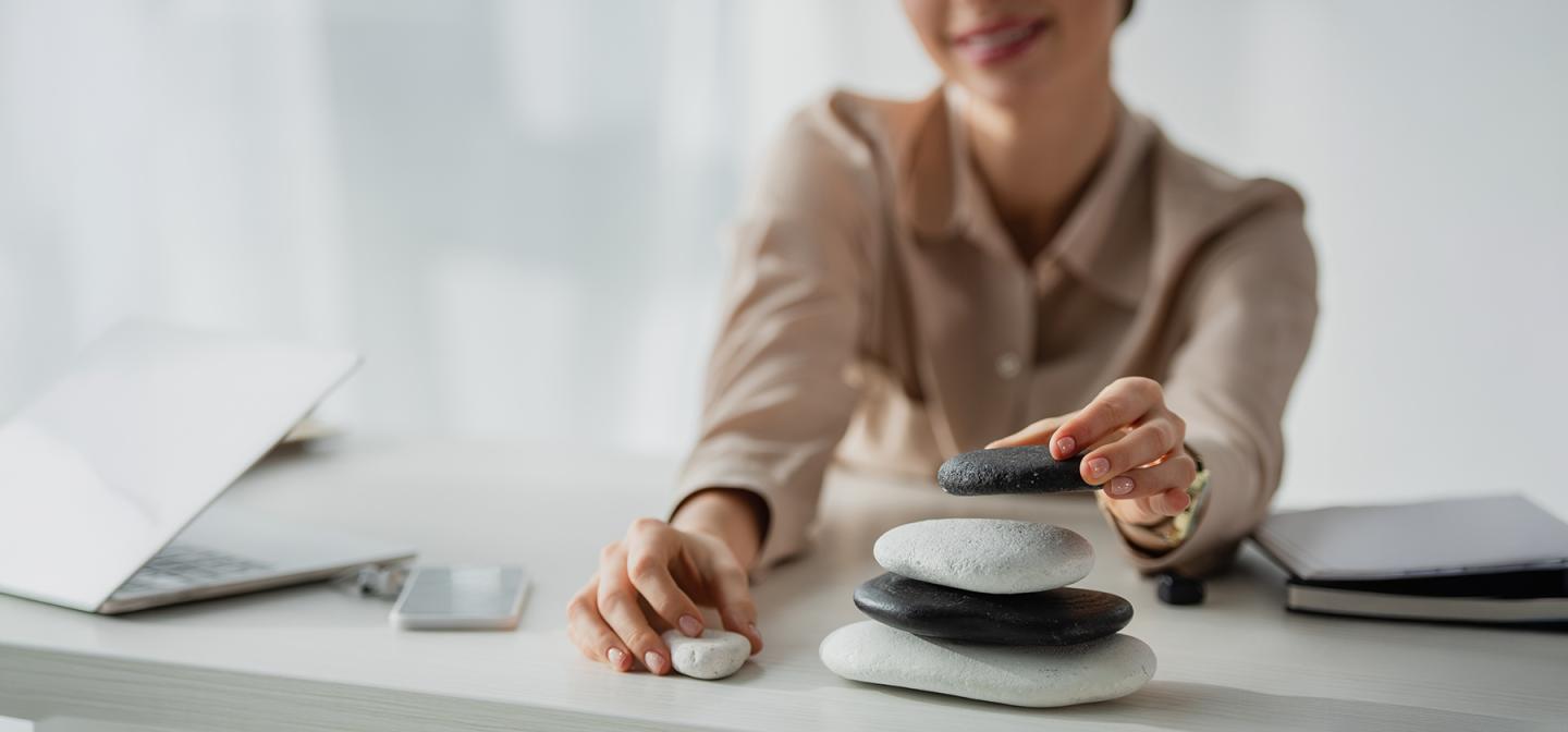 Leader stacking balanced stones on desk symbolizing a 10-minute leadership reset for resilience and focus