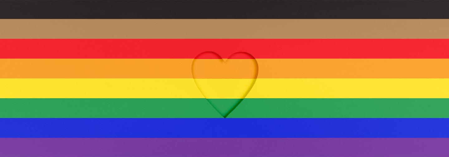 Heart on inclusive Pride flag background for LGBTQ+ Pride Month booklist.