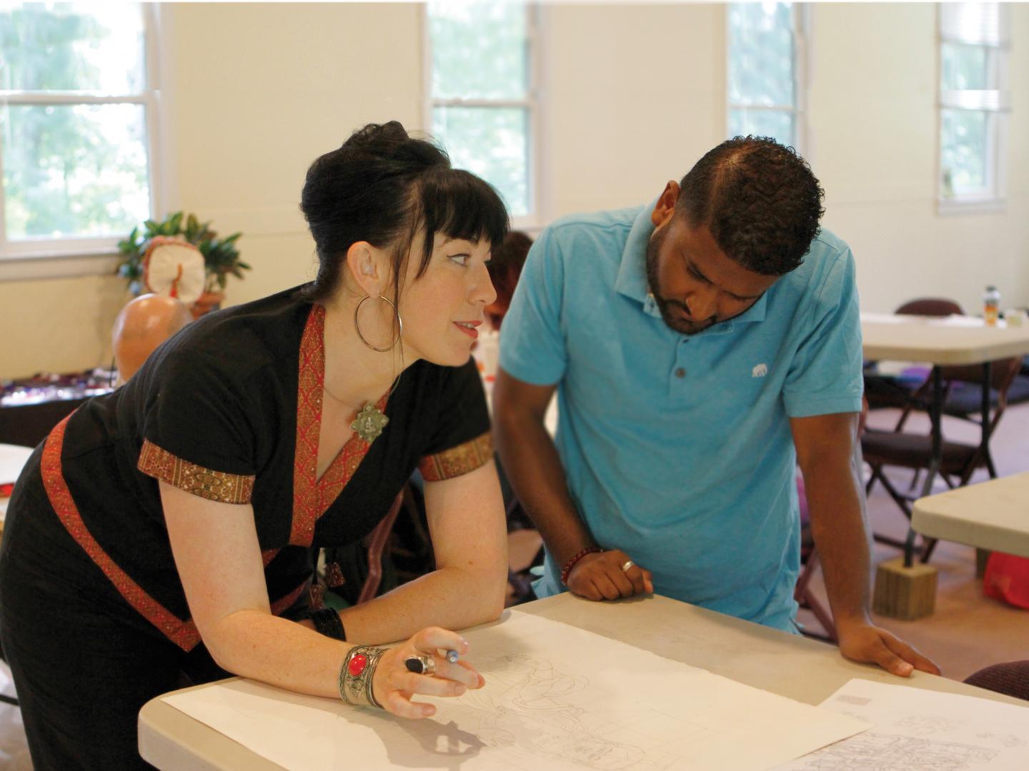 2 people drawing something on a large piece of paper