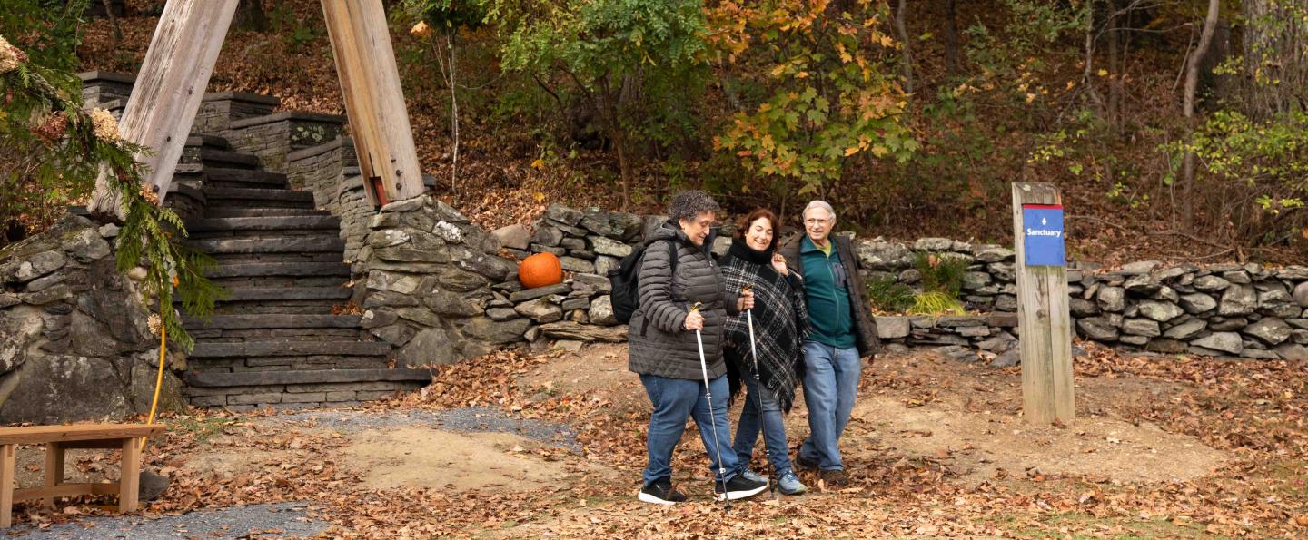 Three people walk on Omega's campus in autumn