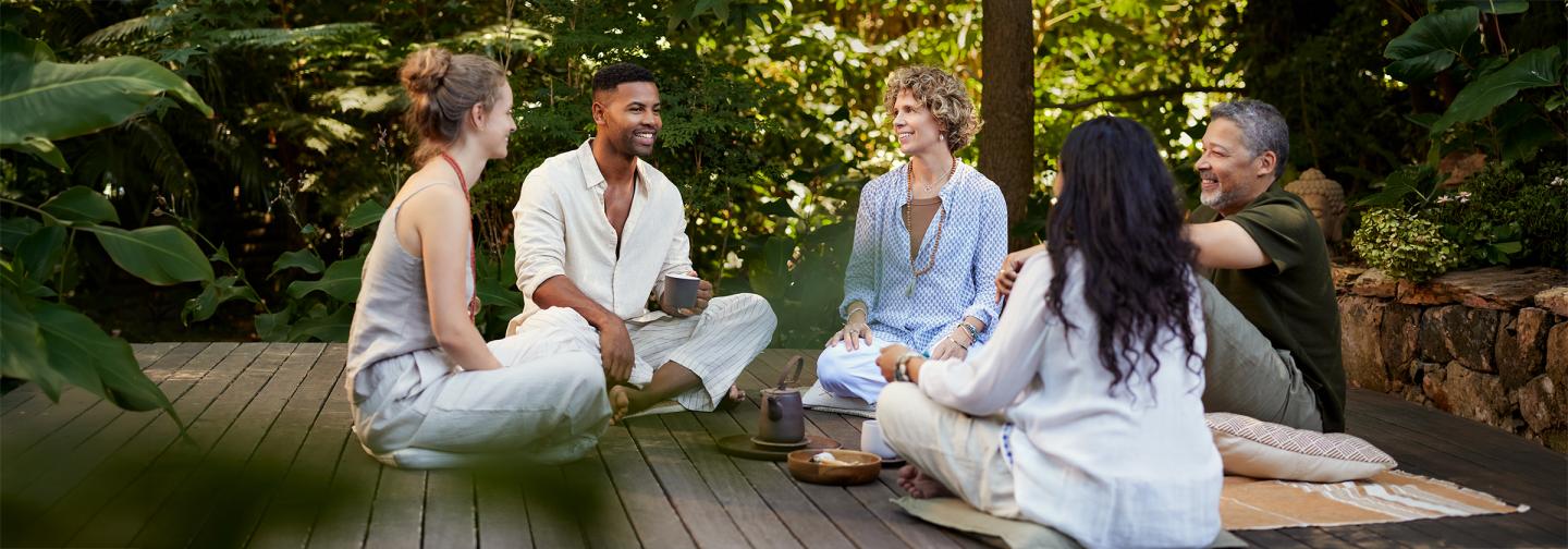 Group of adults gathering outdoors for mindful conversation and connection during an analog wellness retreat focused on presence, community, and digital well-being.