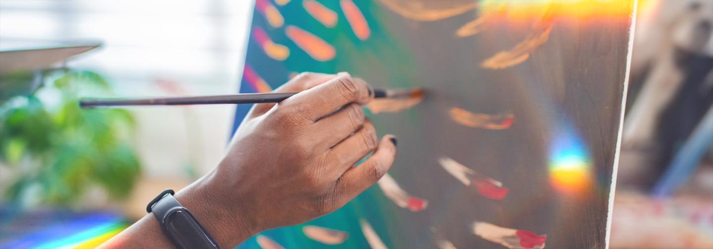 Close-up of a person painting abstract art on canvas, illustrating creativity and mental well-being