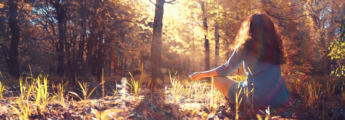 Woman meditating in forest in autumn