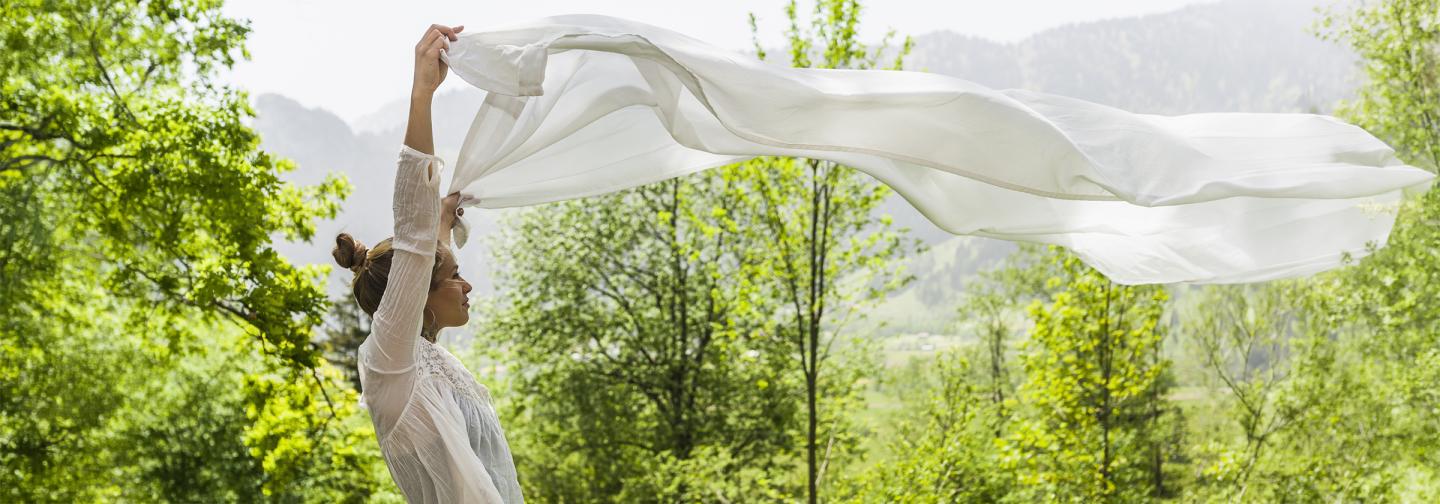 Person outdoors holding a flowing white scarf, symbolizing moving beyond survival mode through healing, resilience, and emotional well-being.